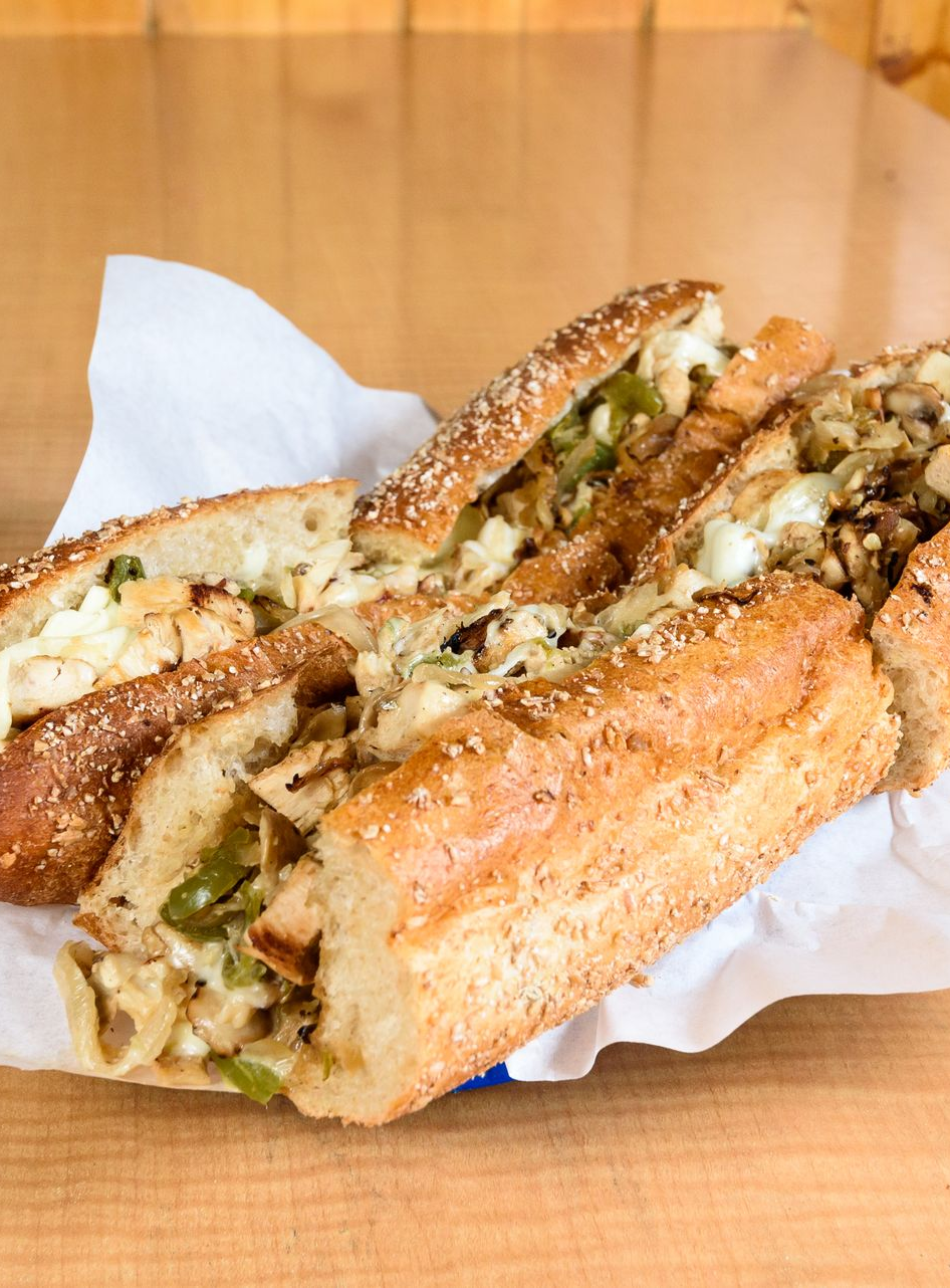 Sandwich cut in half on parchment paper, stuffed with meat and melted cheese on a wooden table