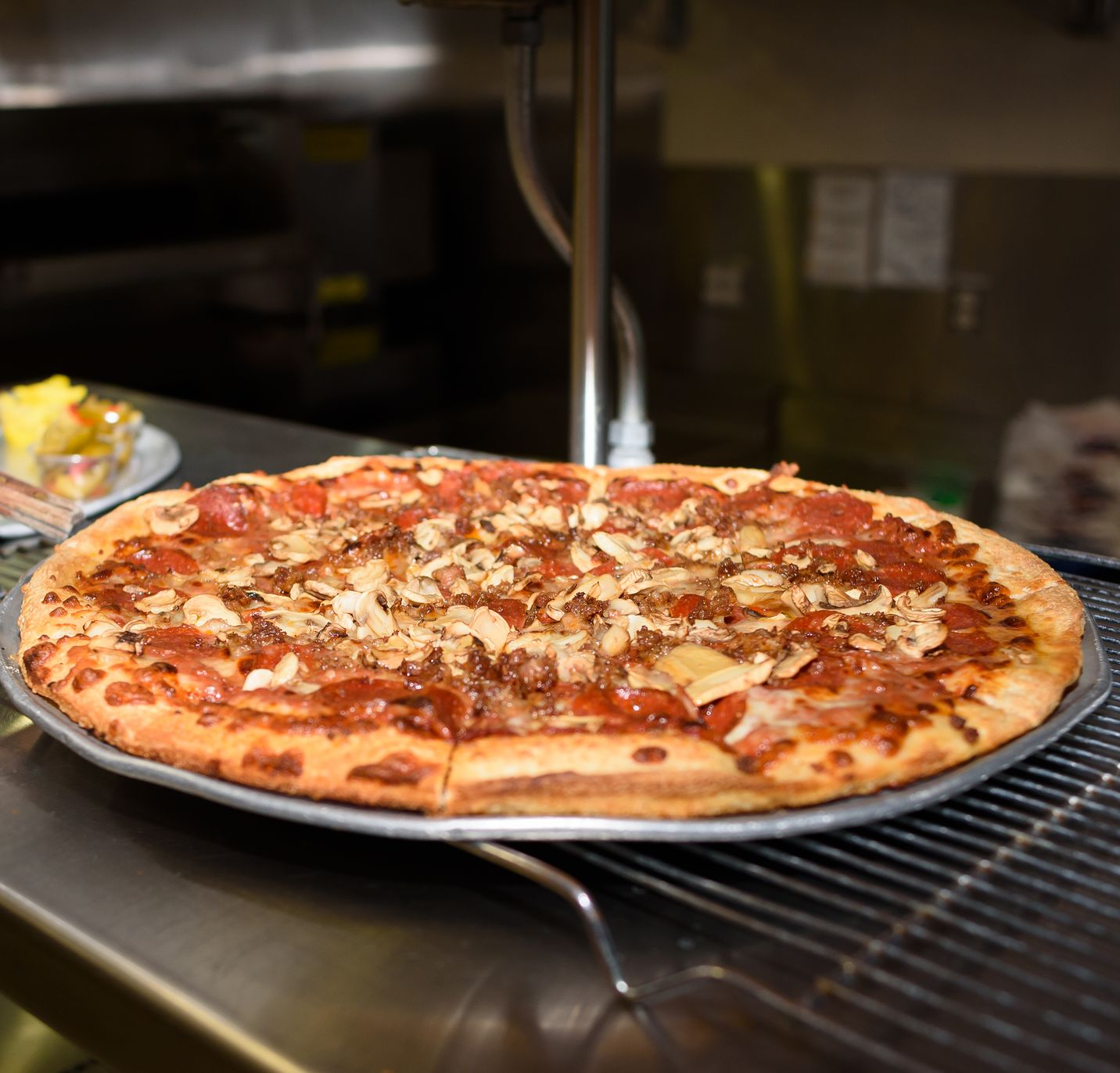 Large pepperoni and cheese pizza on a metal rack in a kitchen