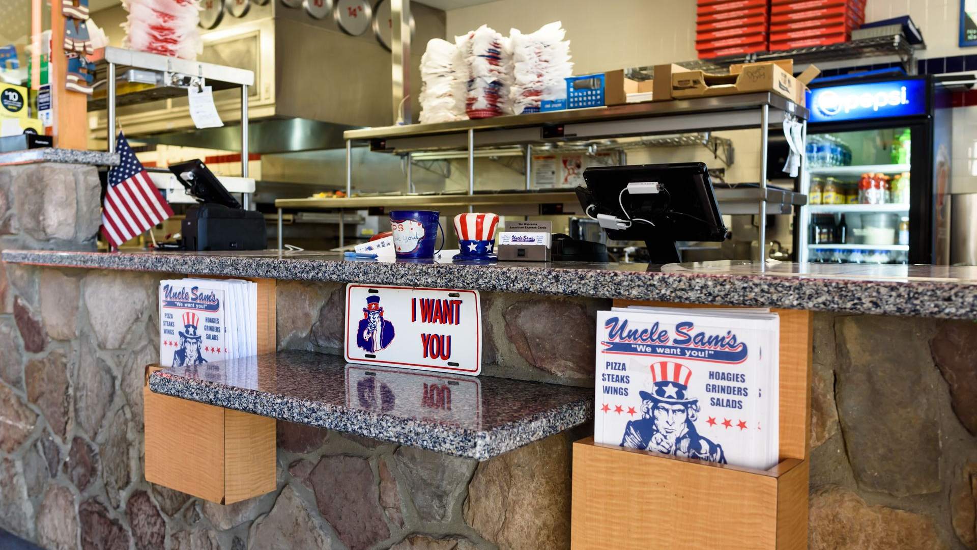 Takeout counter with granite front, red pizza boxes, and a Pepsi fridge in a casual restaurant