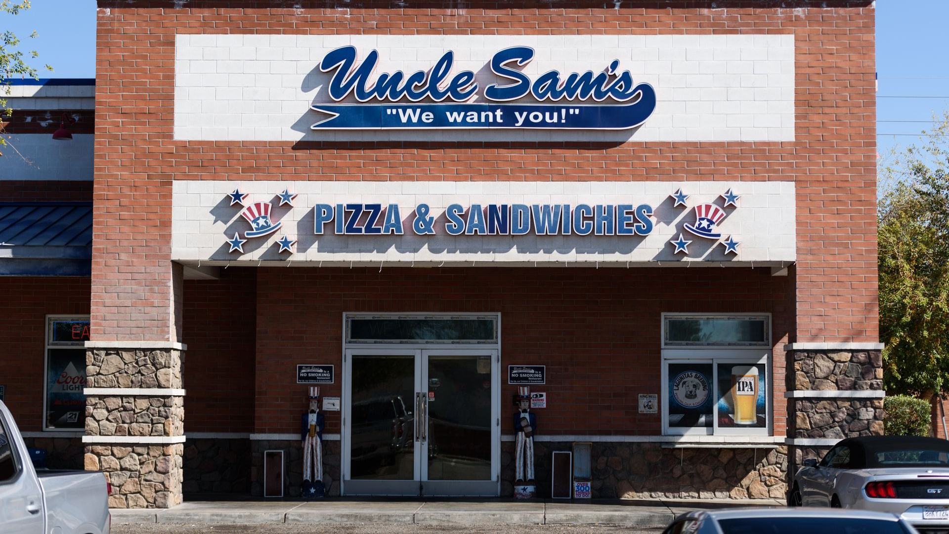Storefront of Uncle Sam’s with a pizza and sandwiches sign above the entrance