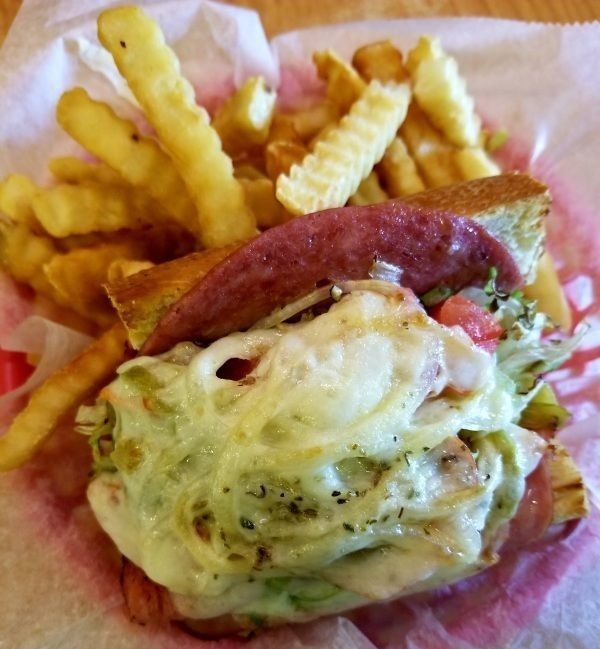 Cheesesteak sandwich with melted cheese and fries on red paper tray liner