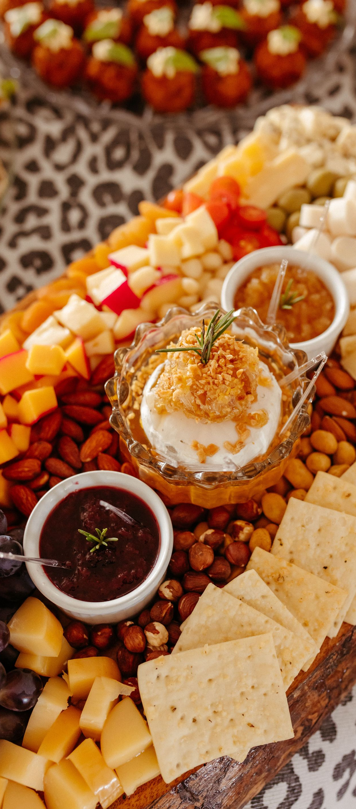 Charcuterie board with cheeses, crackers, meats, fruit, and dips arranged on a wooden platter