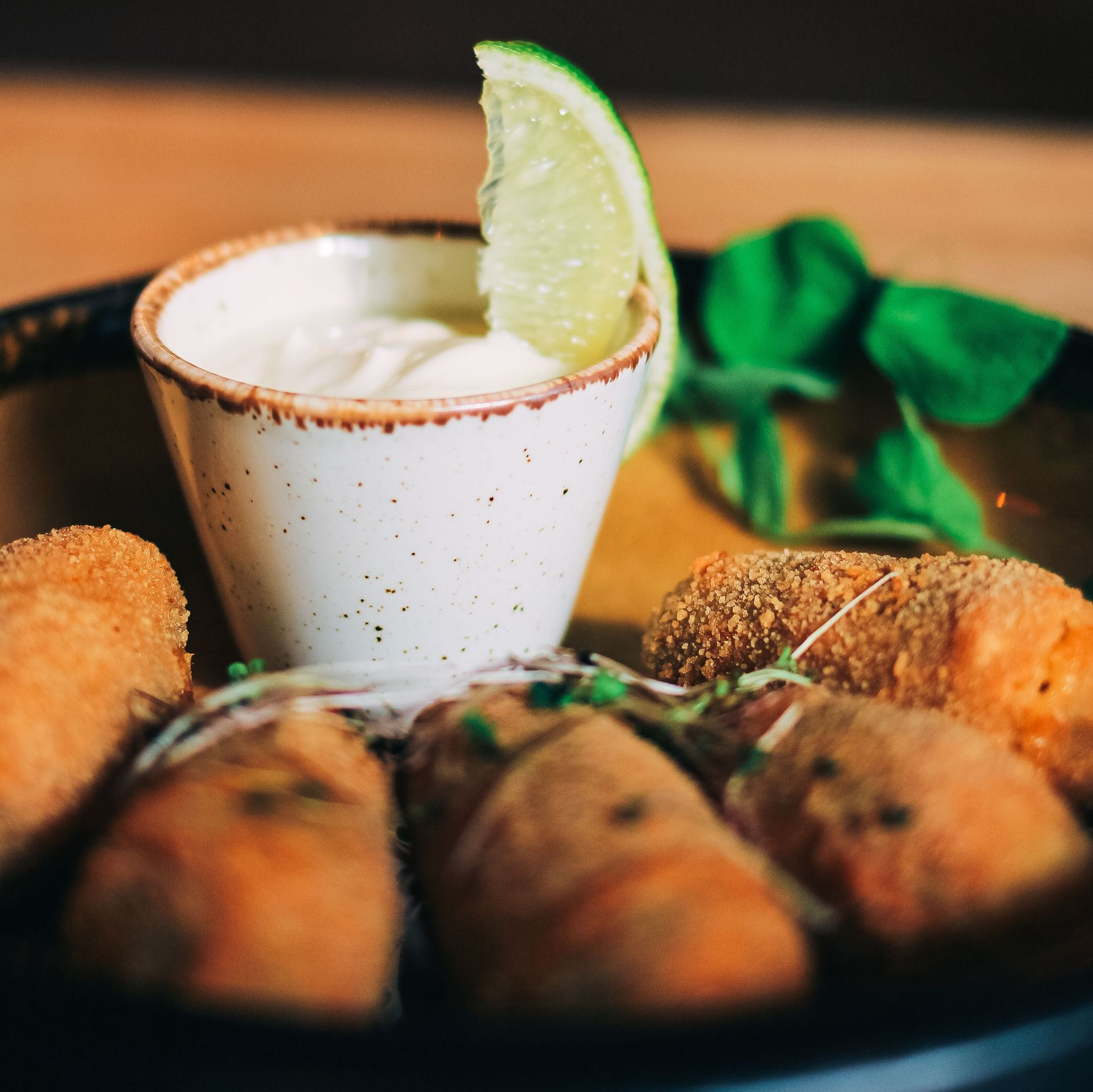 Fried appetizers with a lime wedge dipping sauce on a dark plate