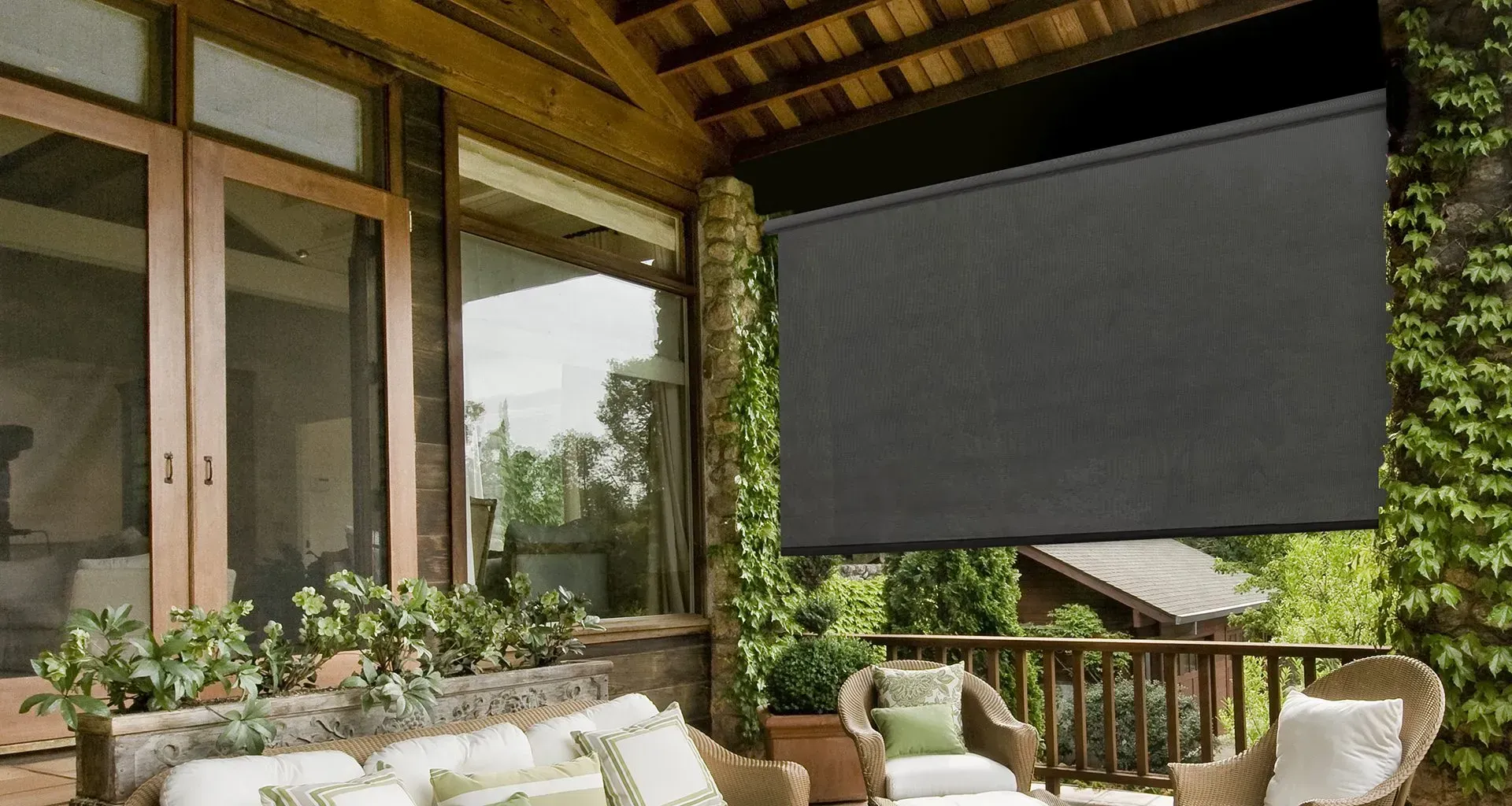 Patio with large black retractable sun shade; seating, plants, and wooden structure.