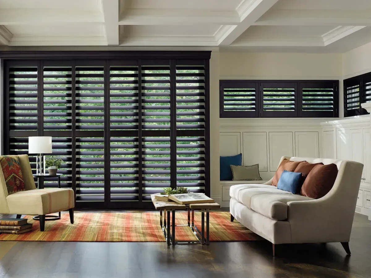 Living room with black shutters, beige couch, and coffee table.