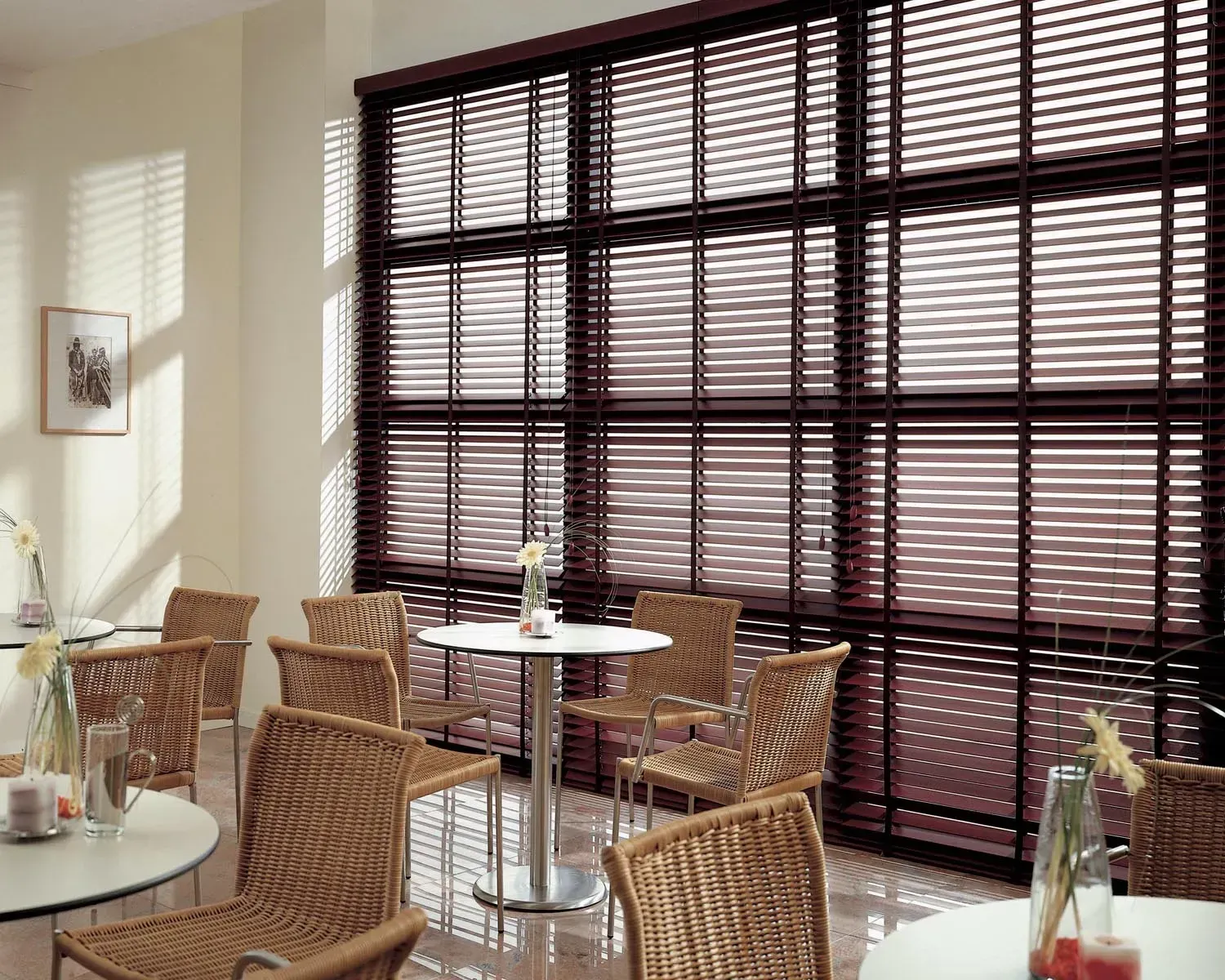 Cafe interior with tables, chairs, and large window with wooden blinds.