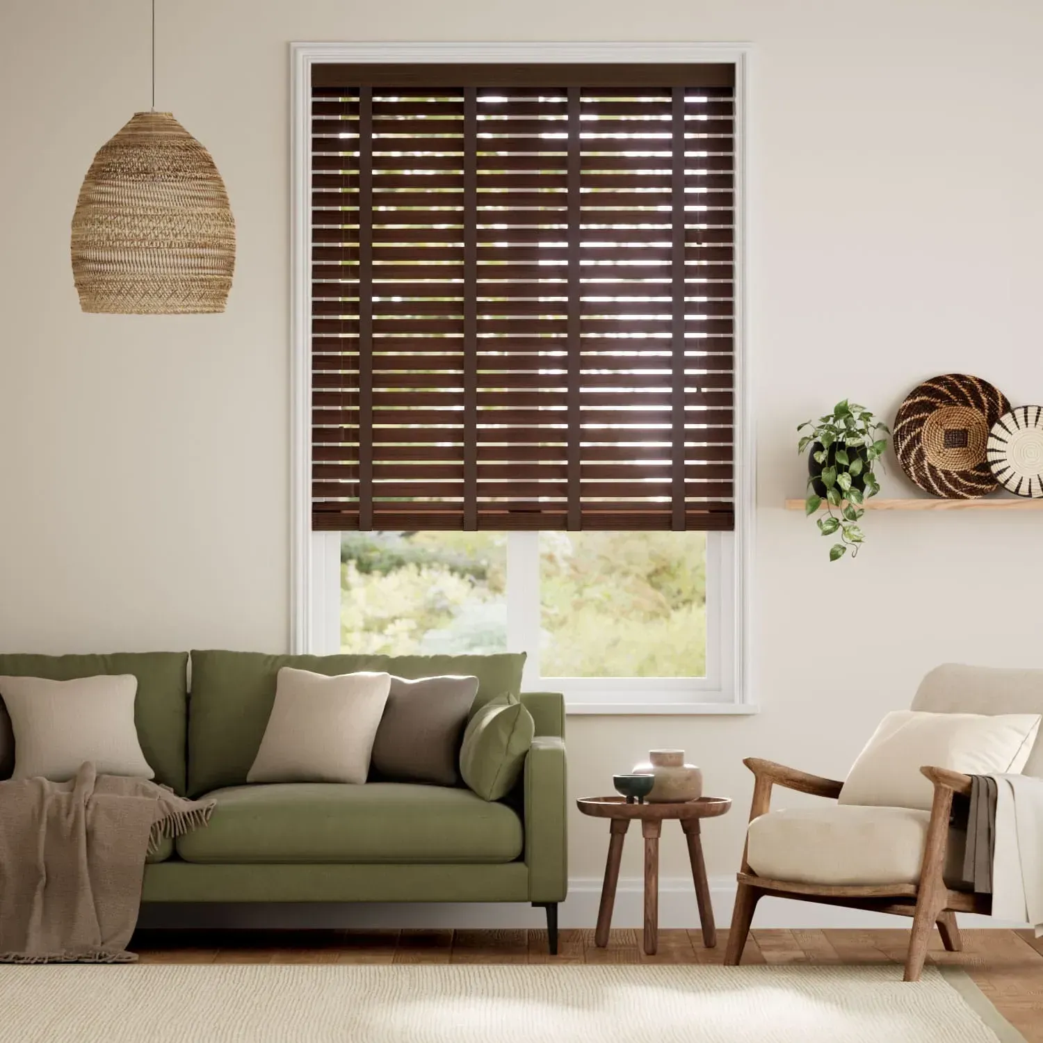 Living room with green sofa, wooden blinds, woven pendant light, and armchair.