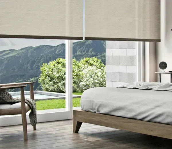 Bedroom with large window, roller shades, bed, chair, and mountain view.