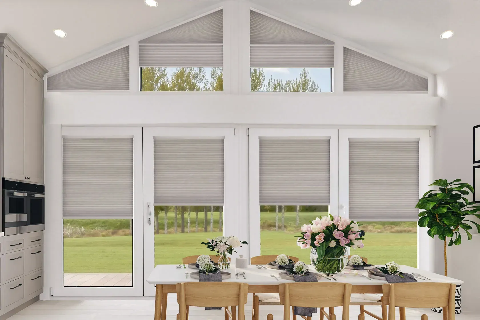 Bright dining room with large windows, light gray pleated blinds, and a white table set for a meal.