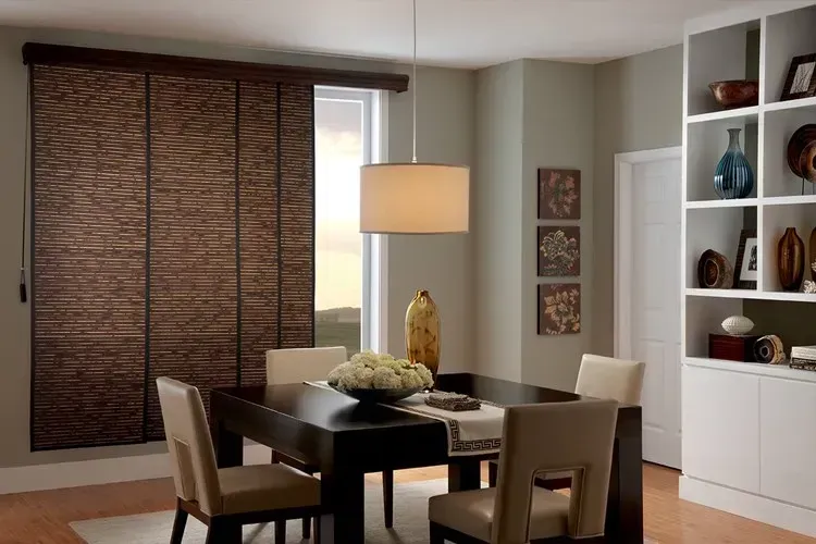 Dining room with a dark wood table, chairs, and woven blinds. A built-in white shelf unit is on the right.