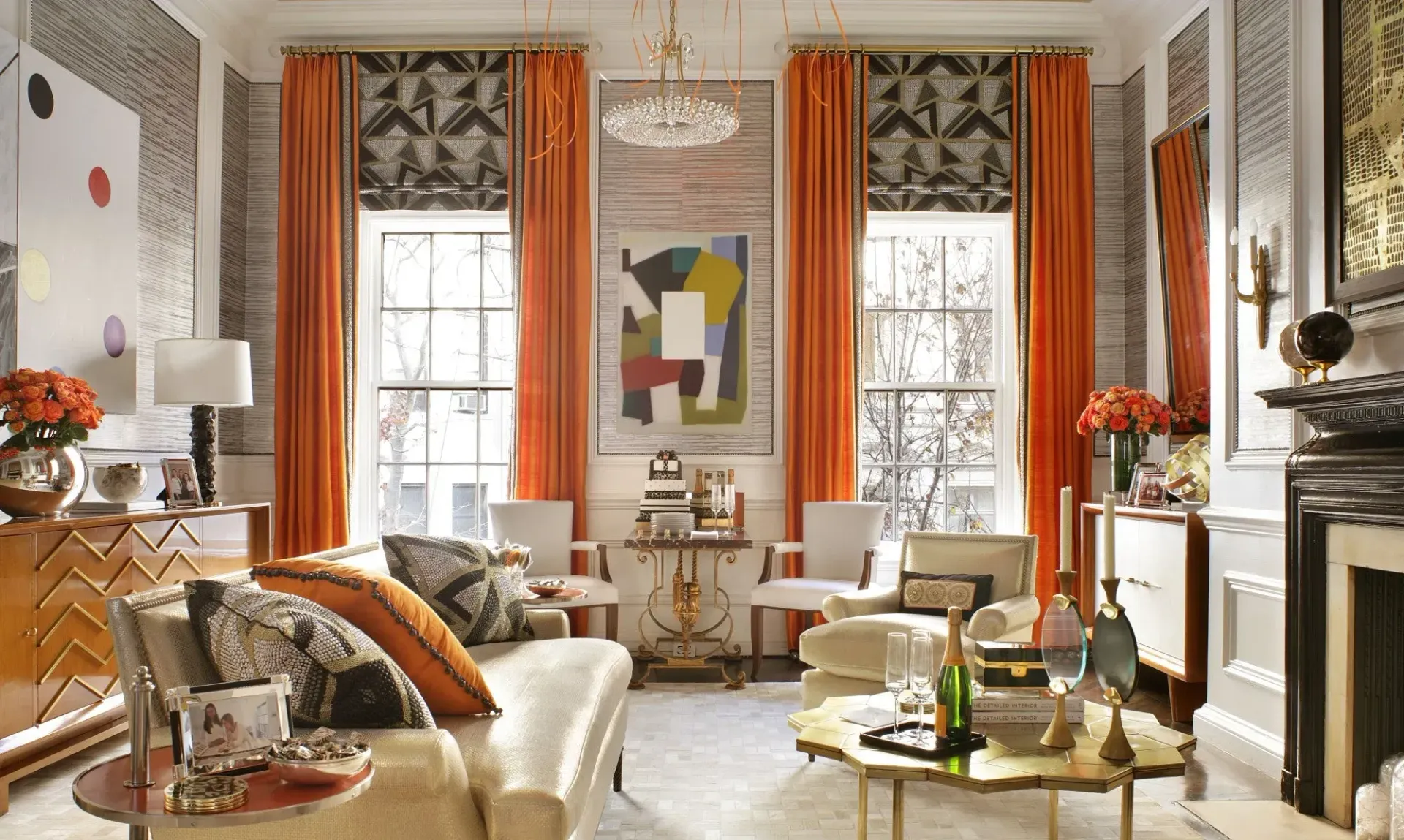 Living room with orange curtains, patterned wallpaper, art, and furniture in a colorful, eclectic style.