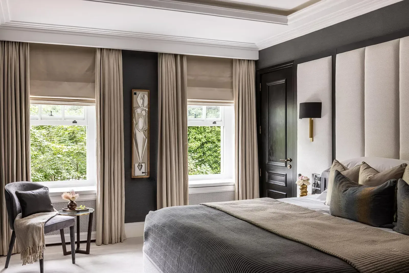 Bedroom with windows, neutral tones, plush bed, chair, and dark gray accent wall.