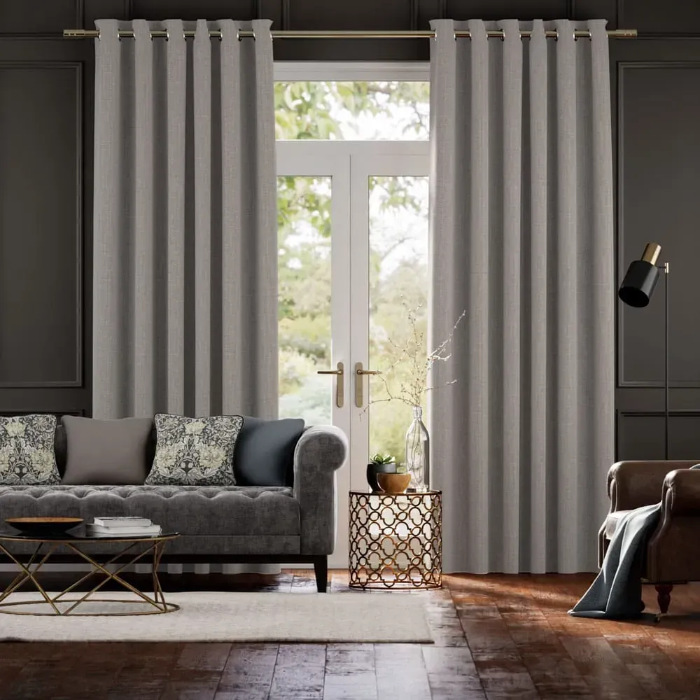 Gray curtains frame a window in a living room, above a sofa, table, and chair.