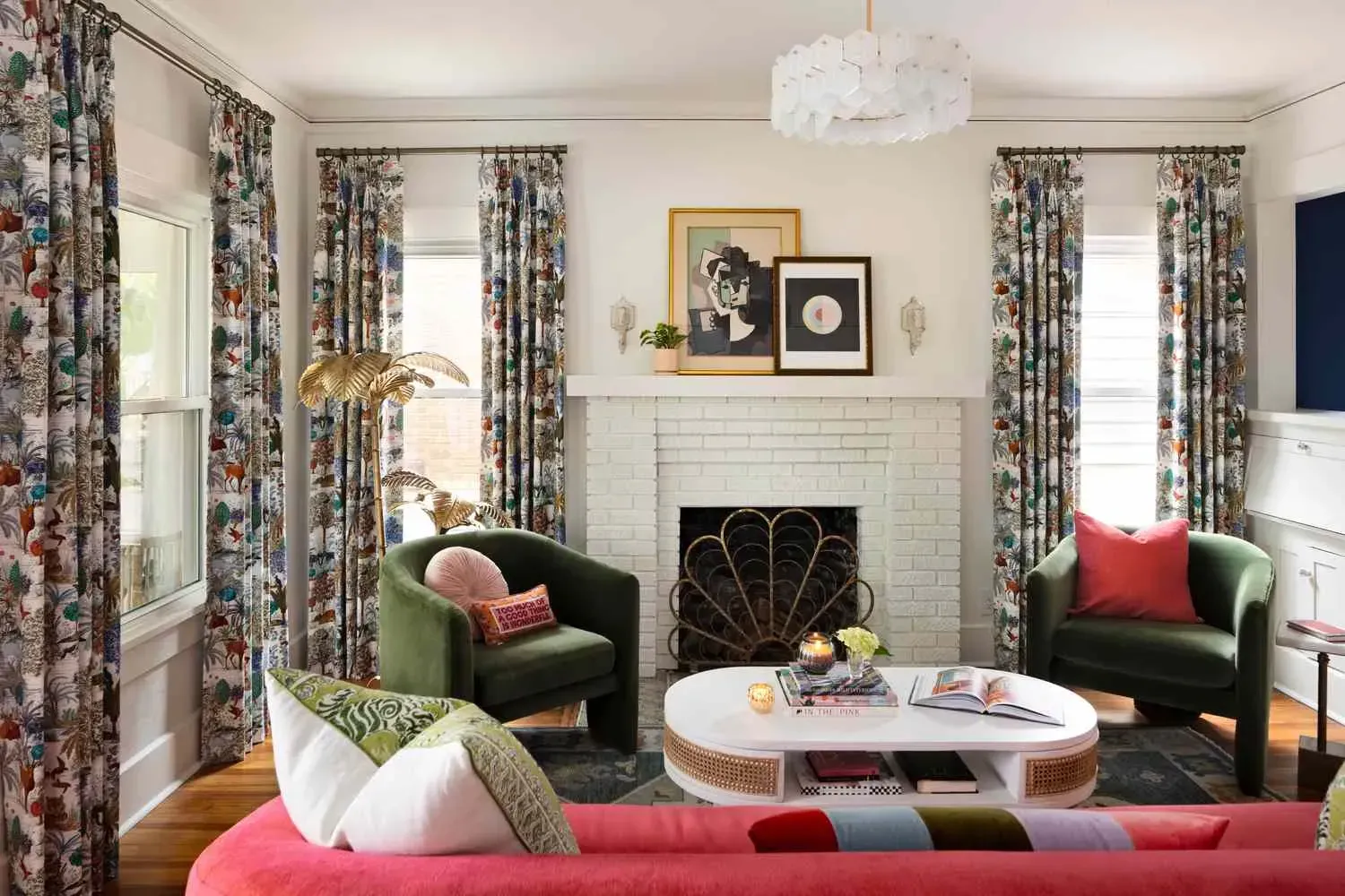Living room with floral curtains, green armchairs, pink sofa, and white fireplace.