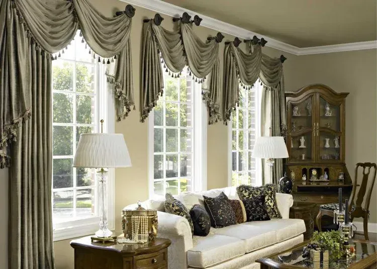 Living room with beige walls, windows with ornate drapery, and cream-colored furniture.