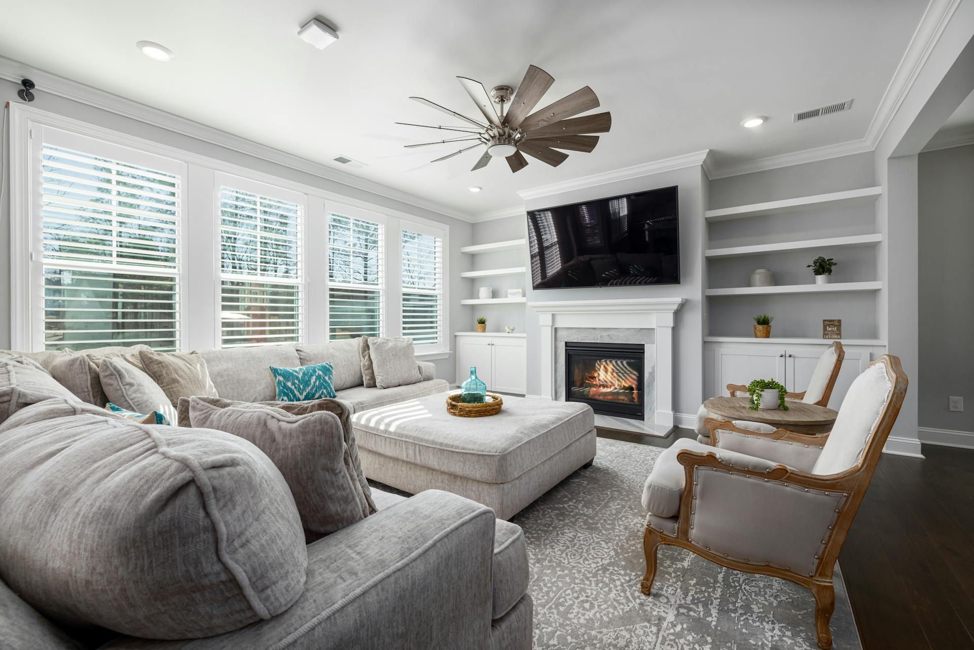 Cozy living room with fireplace, built-in shelves, large sectional sofa, and window blinds.