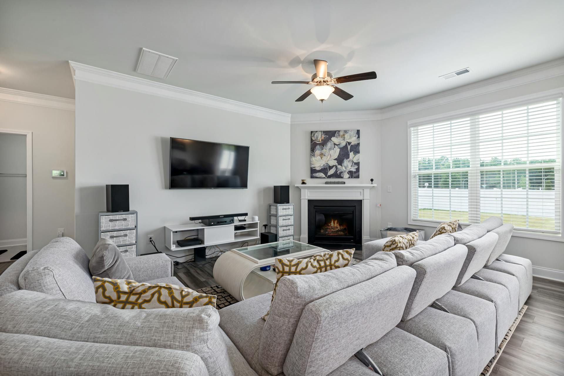 Spacious living room with sectional sofa, fireplace, and large windows overlooking a lake.