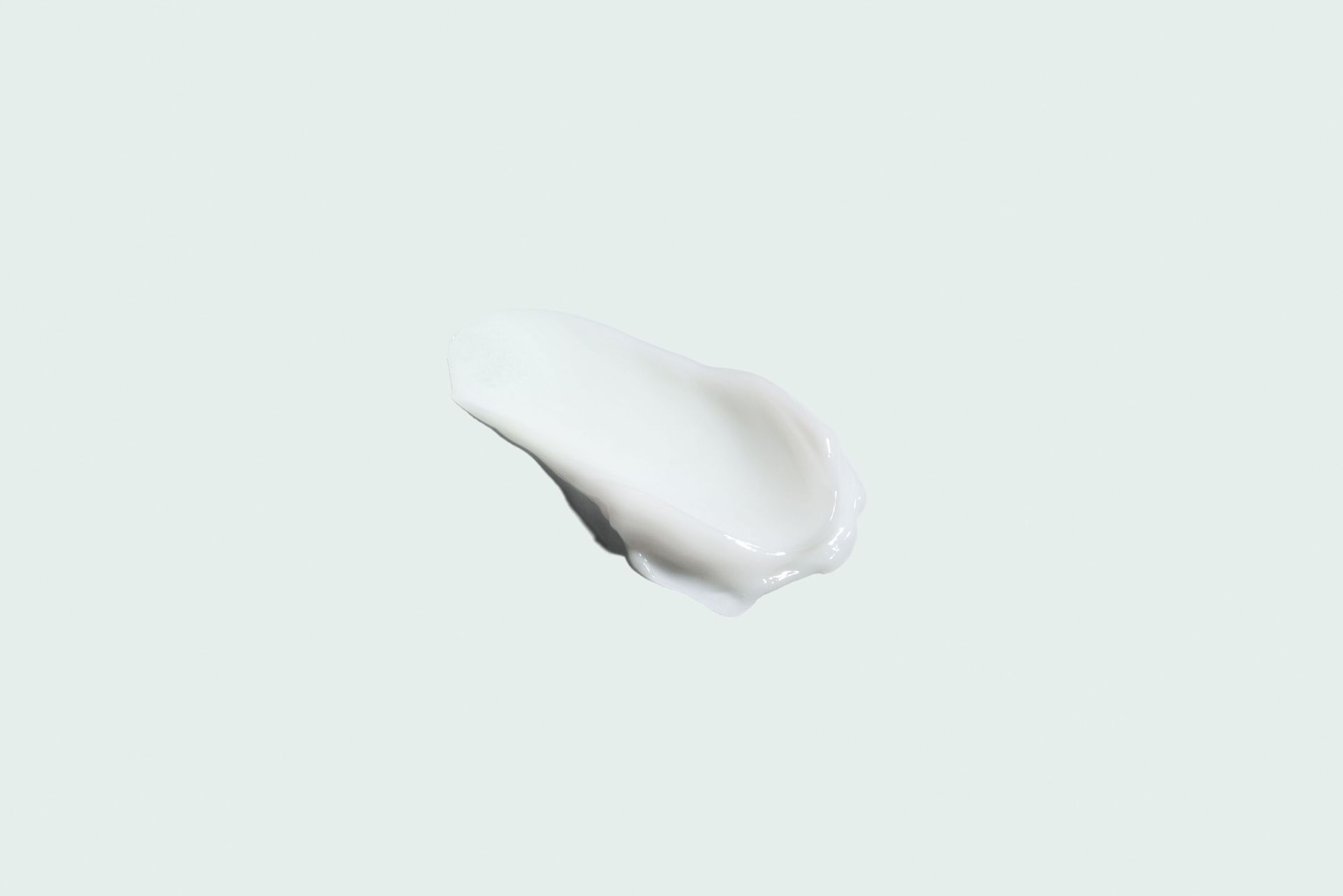 Swirl of white cream on a pale green background.