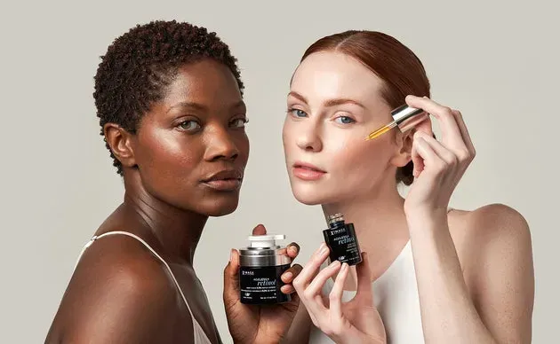 Two women applying skincare serum, one with dark skin and one with fair skin.