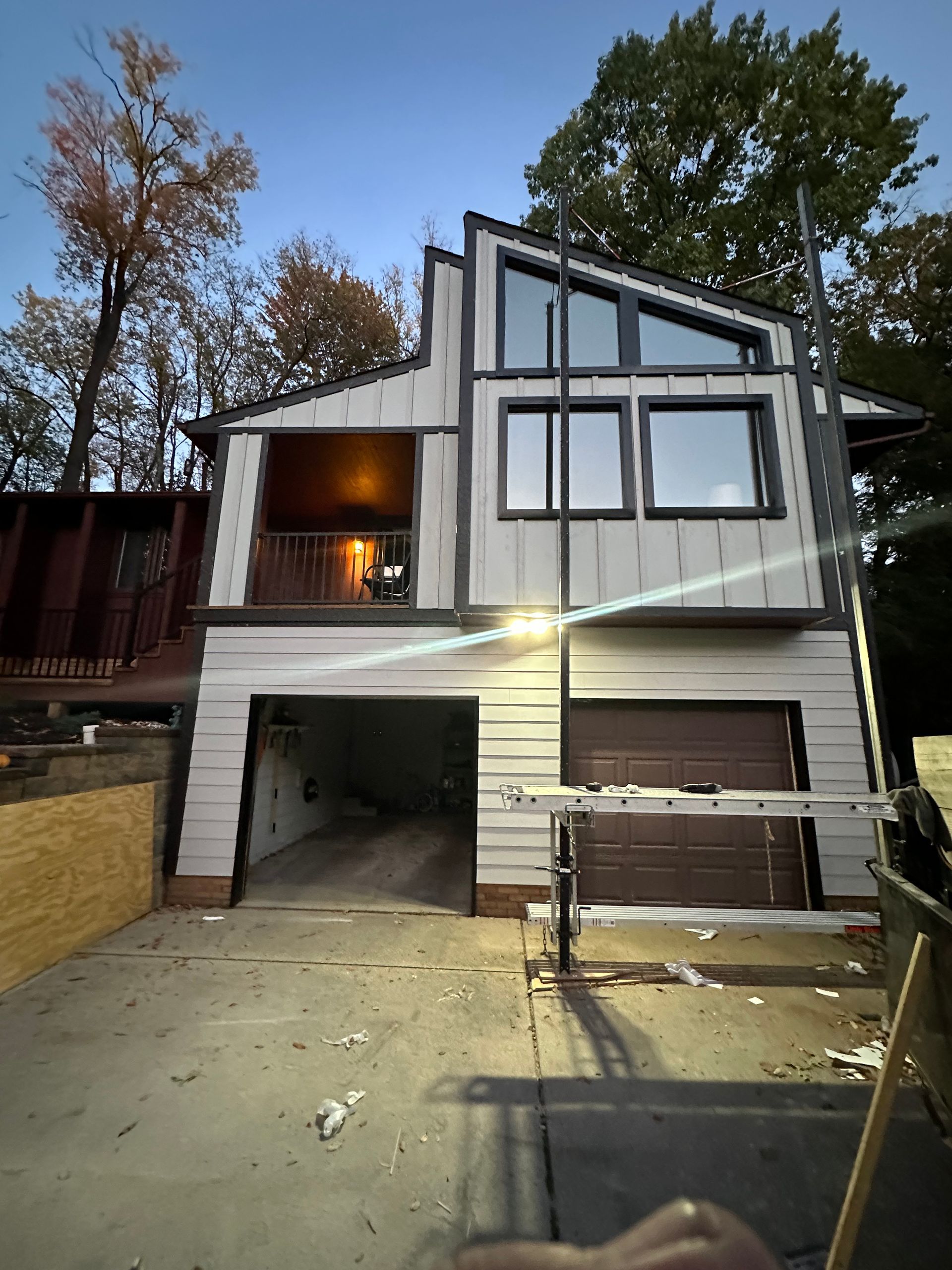 Two-story house with a garage, undergoing construction. The house has a modern design with large windows and light siding.