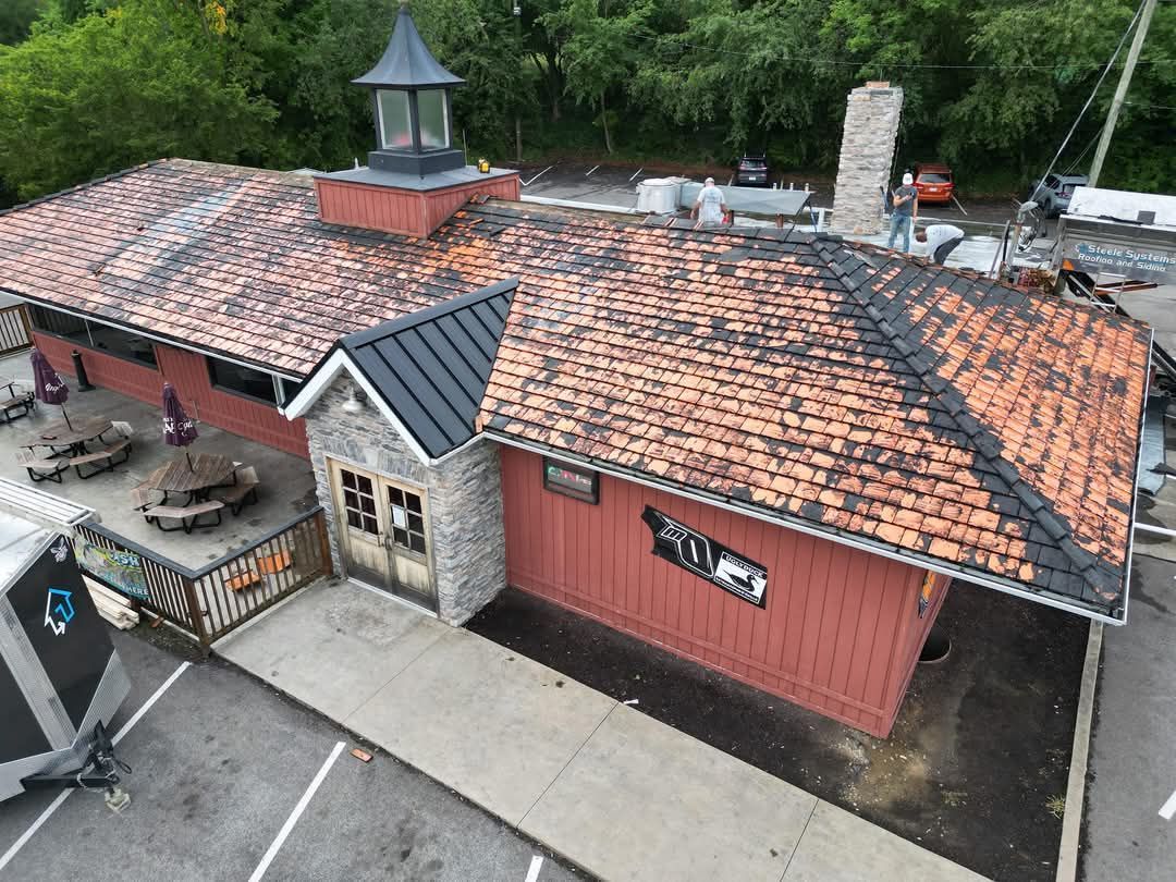 An aerial view of a red building with a brick roof, stone facade, and a chimney. 