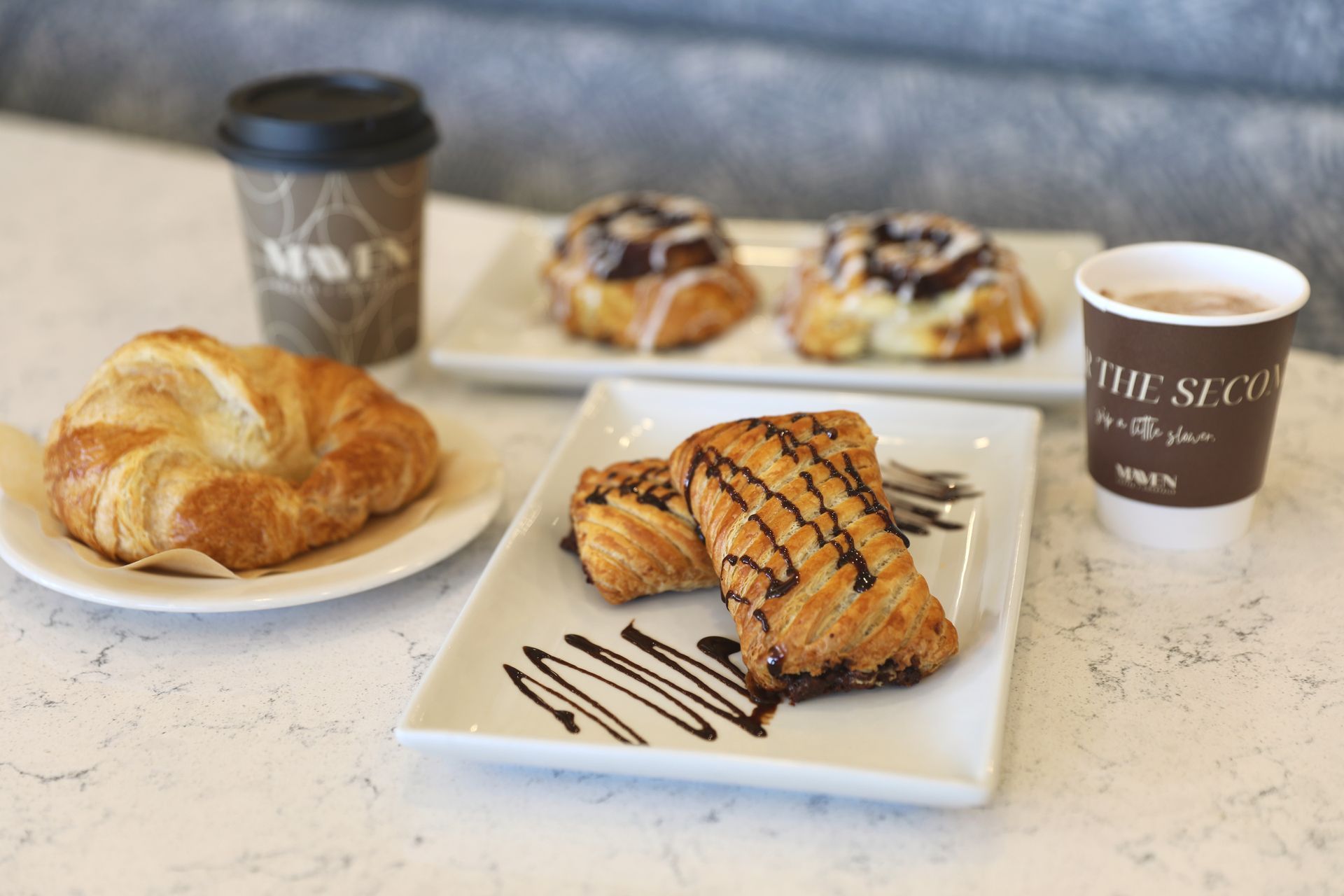 A table topped with plates of pastries and a cup of coffee.