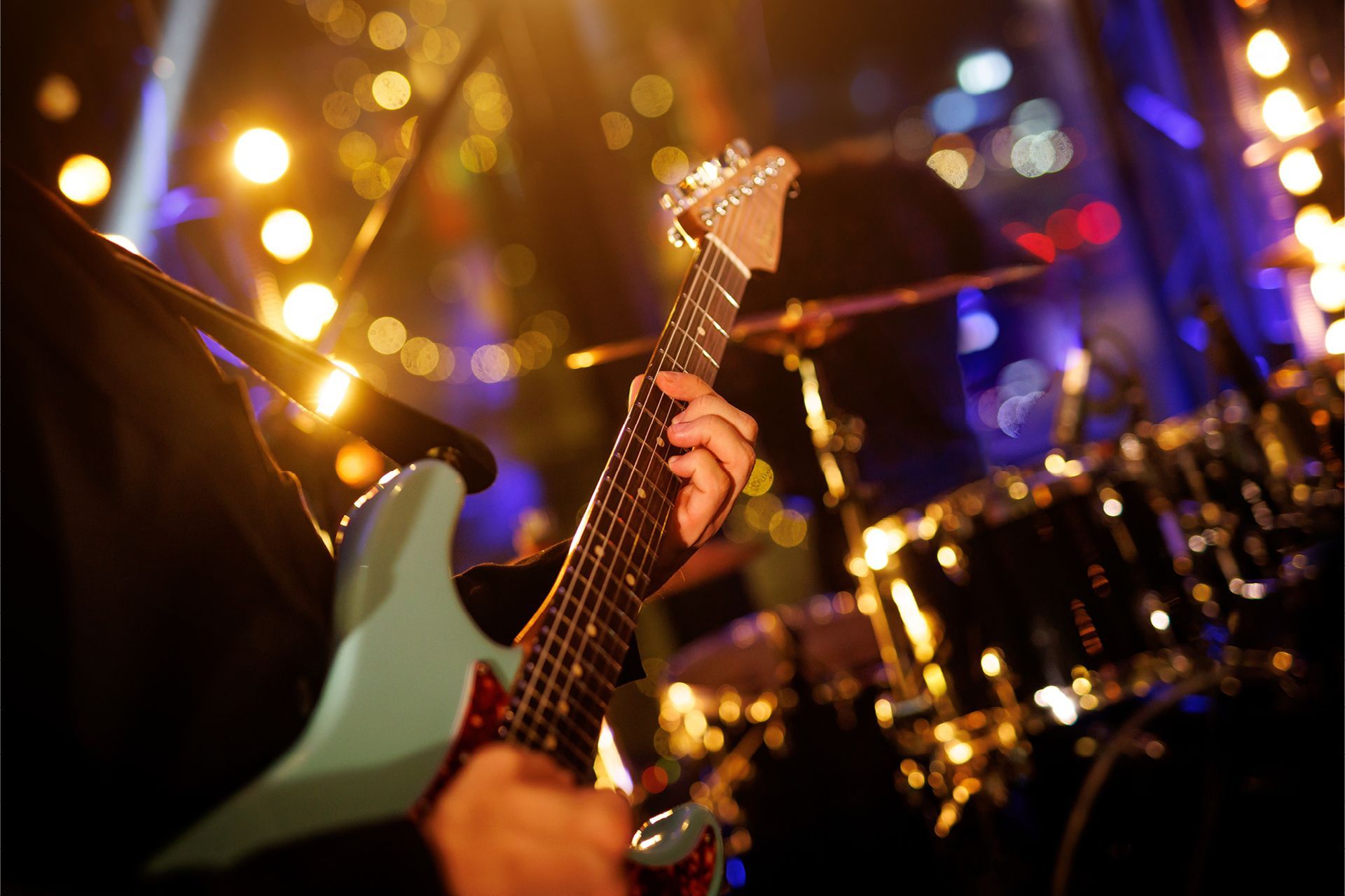 A person is playing an electric guitar on a stage.