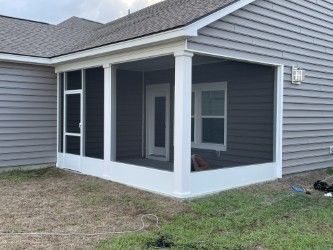 Screened porch attached to a gray house, white trim, door, and window.
