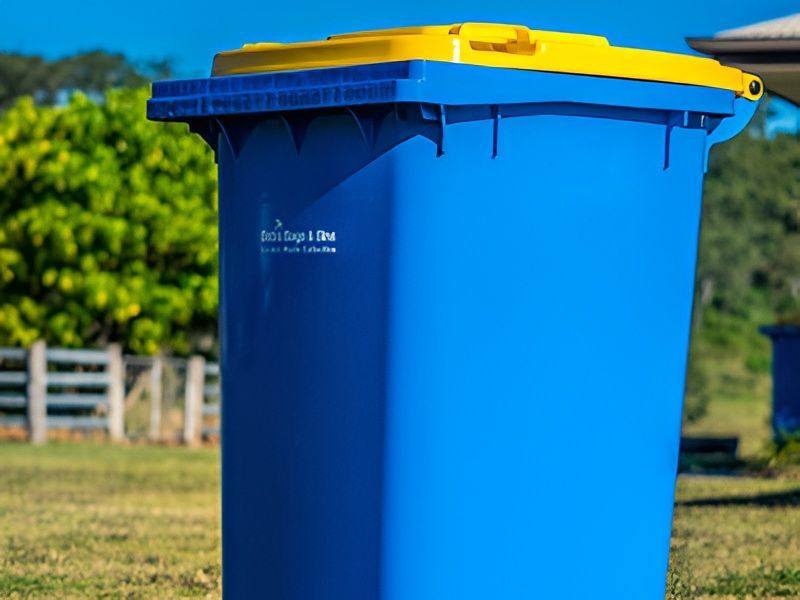 Blue and Yellow Recycling Bin in a Yard With a Green Background — Bobs Bags & Bins in Mackay, QLD