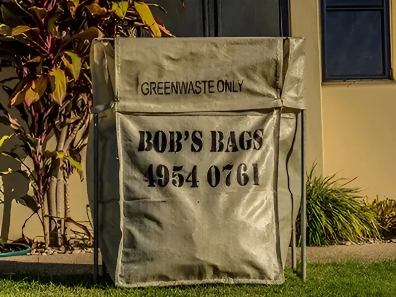 Green waste collection bag on a frame in front of a house, with