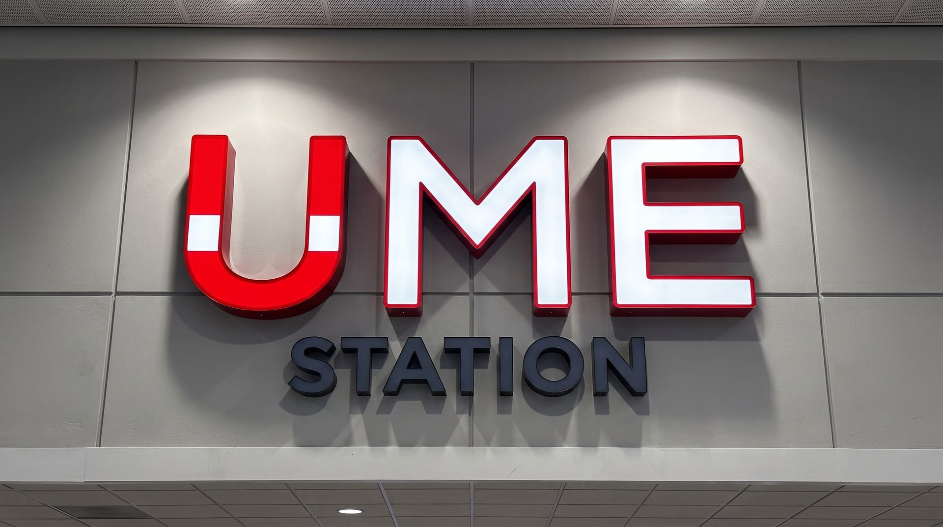Red and black UME STATION sign on a gray building facade