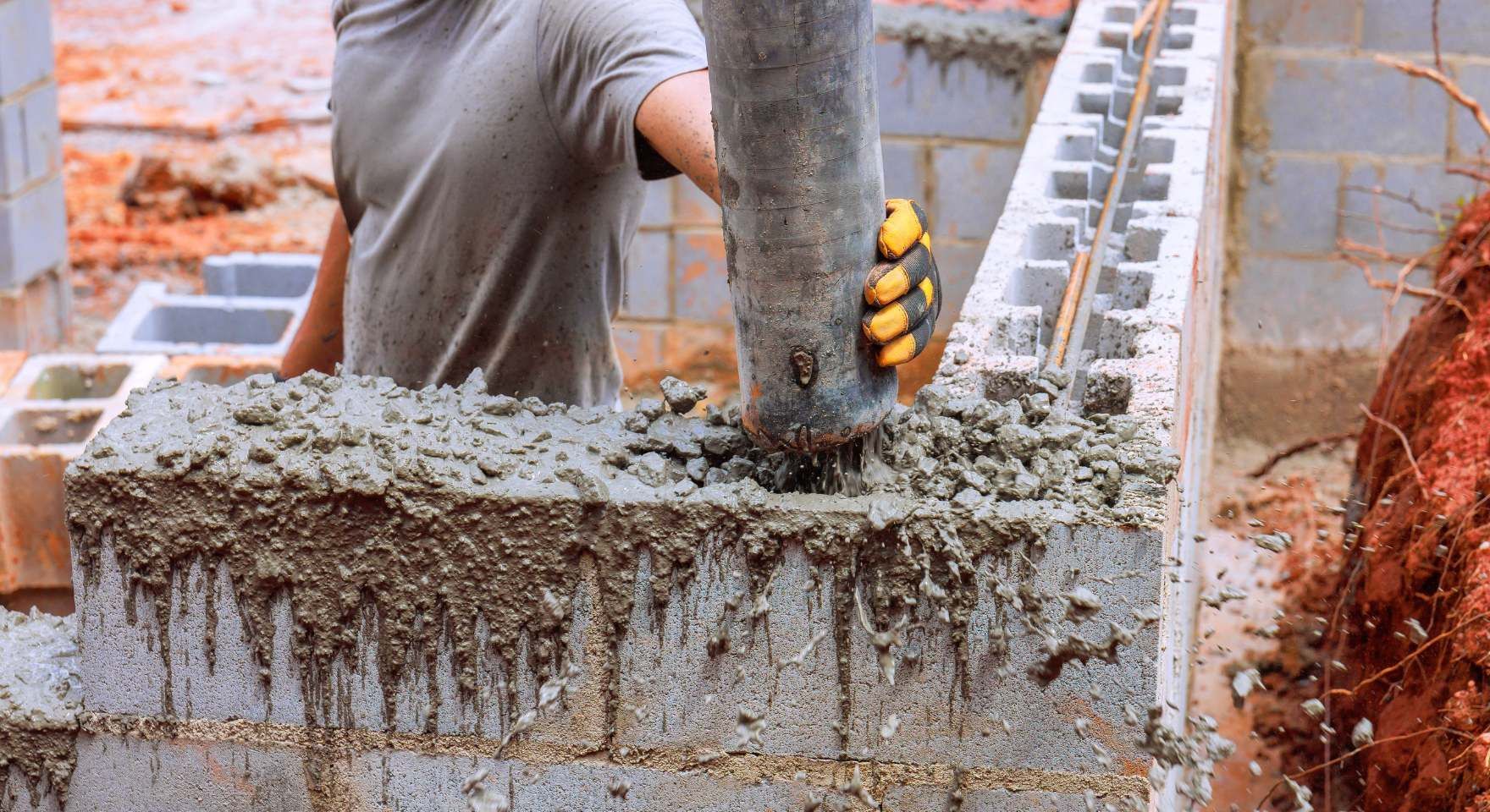 “Worker placing mortar and aligning concrete blocks on a wall under construction during a block and retaining wall service in Santa Ana, CA”