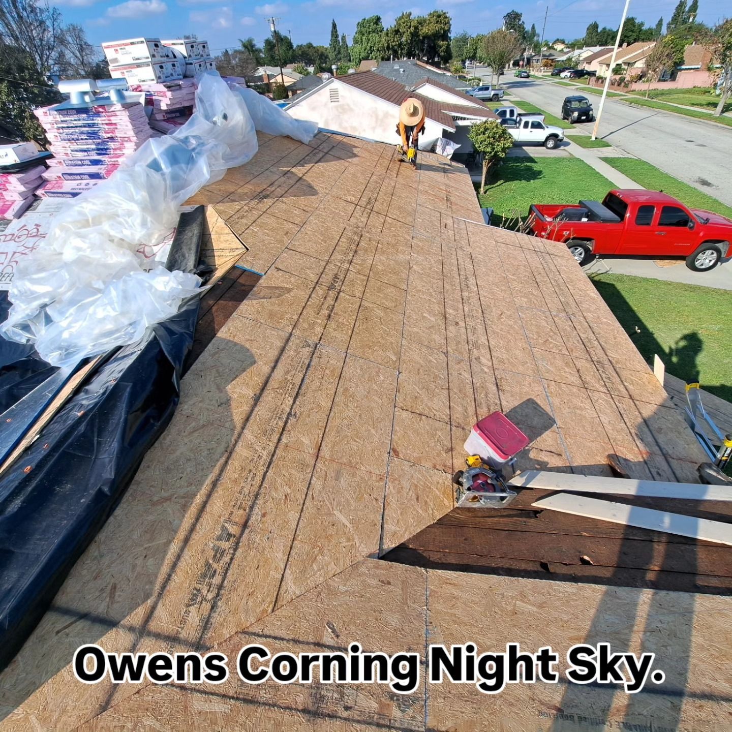 Roof installation with Owens Corning Night Sky shingles being laid on a house rooftop.