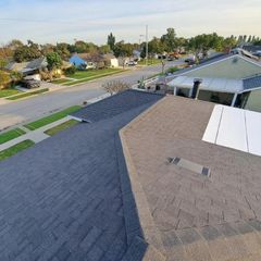 View from a shingled rooftop over a quiet suburban street and neighboring houses