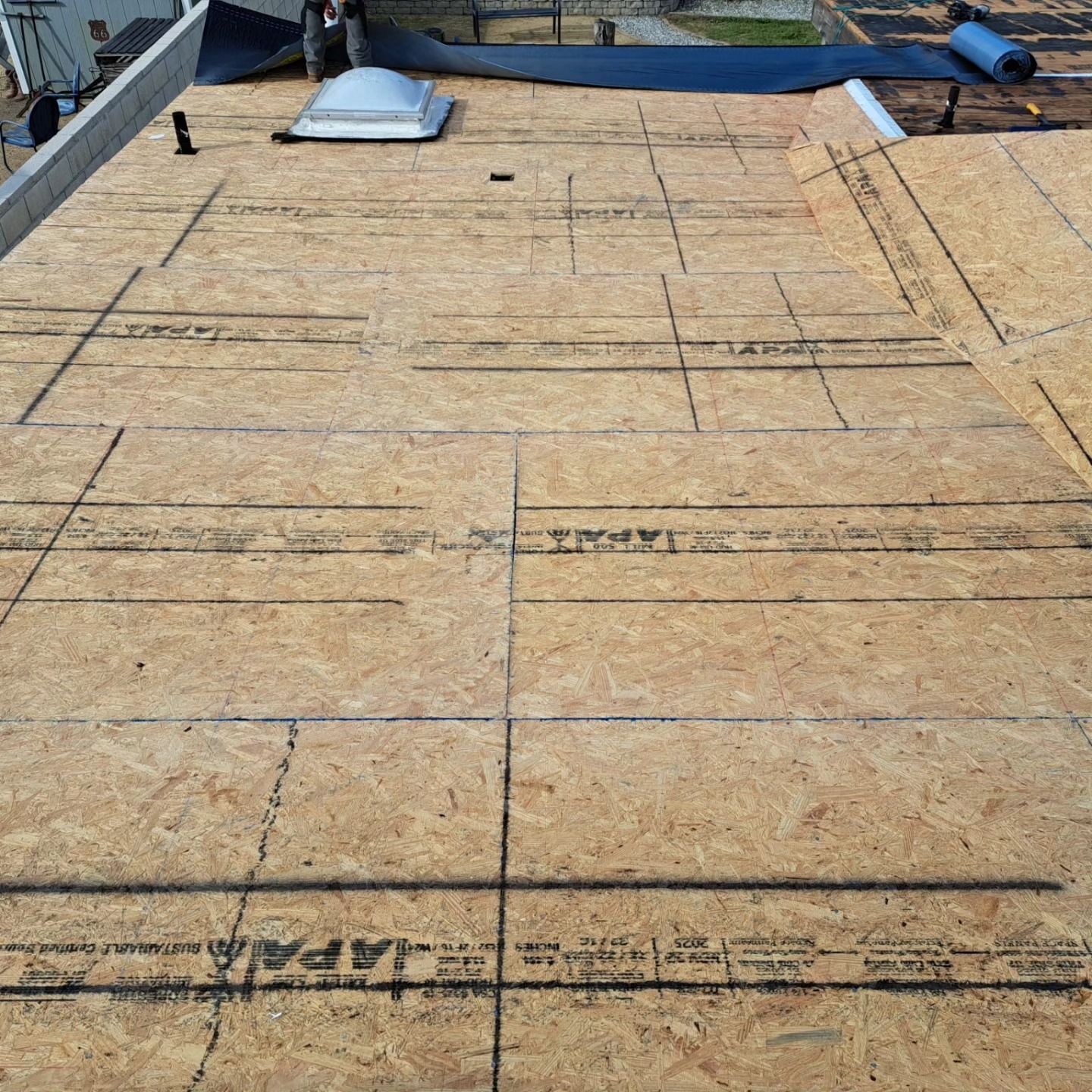 Partially installed roof sheathing on a house, with plywood panels and roof vents visible.