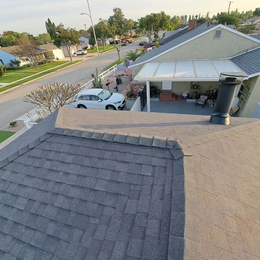 Roof view of a suburban street, driveway with white car, and a house with a covered patio.