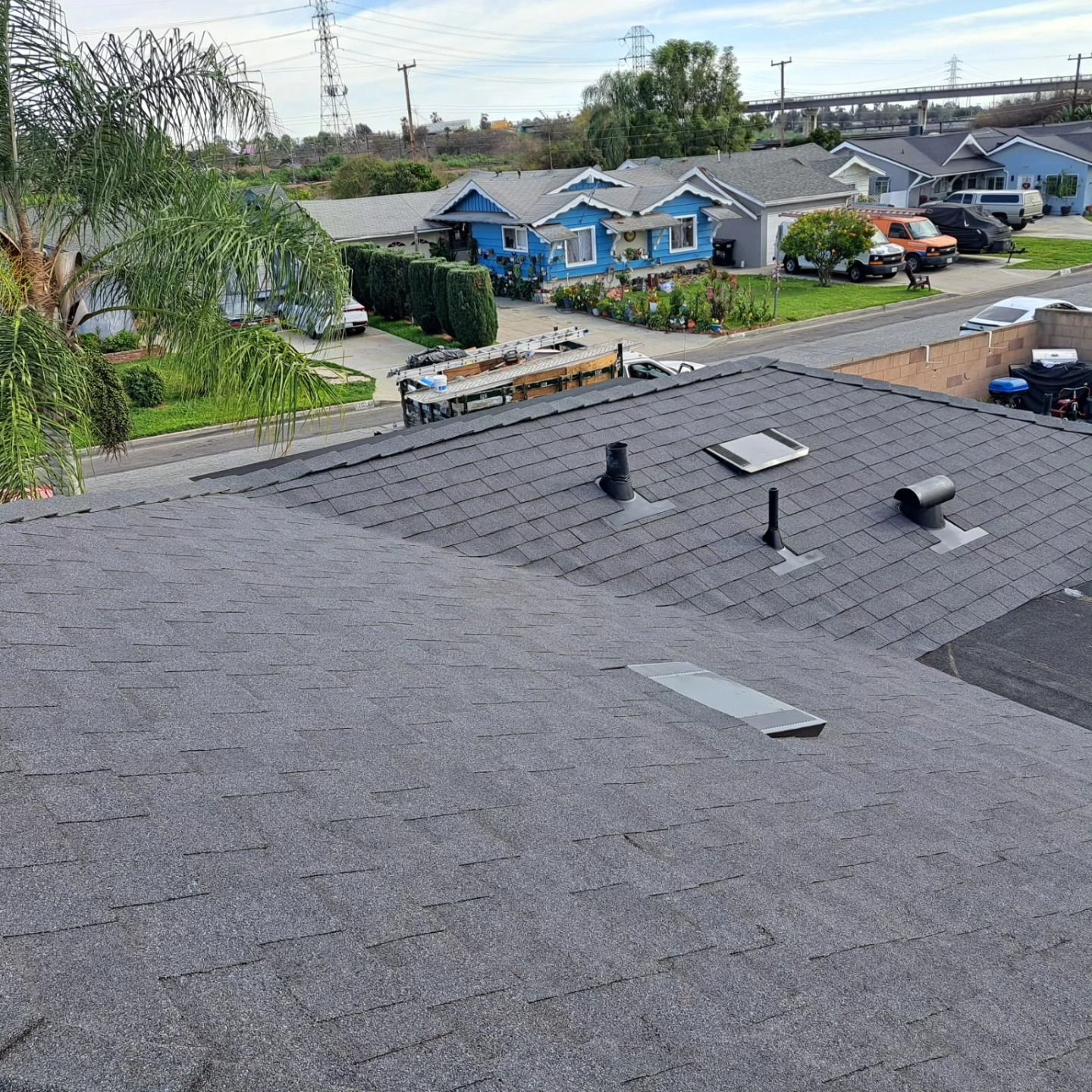 Rooftop with skylights overlooking blue houses and trees in a suburban neighborhood