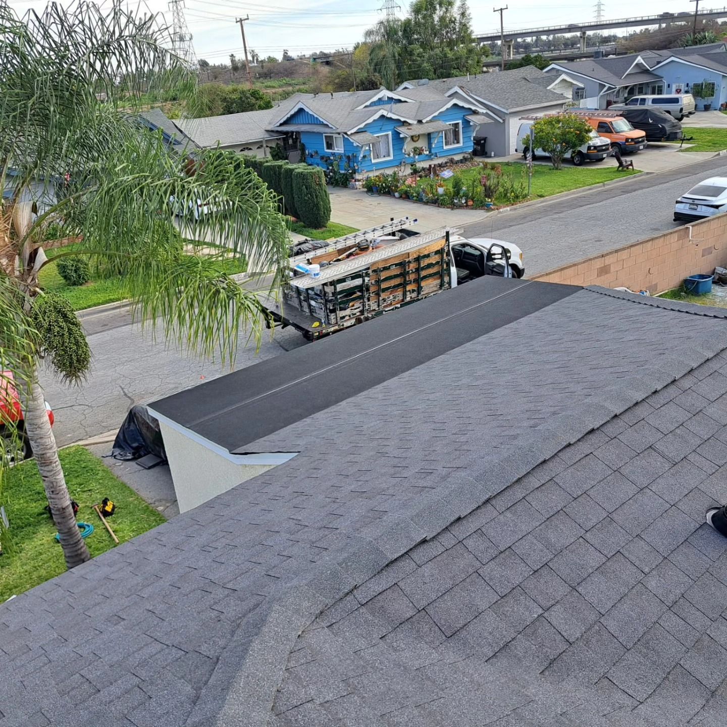 Roof view over a suburban street with houses, trees, and a moving truck parked below