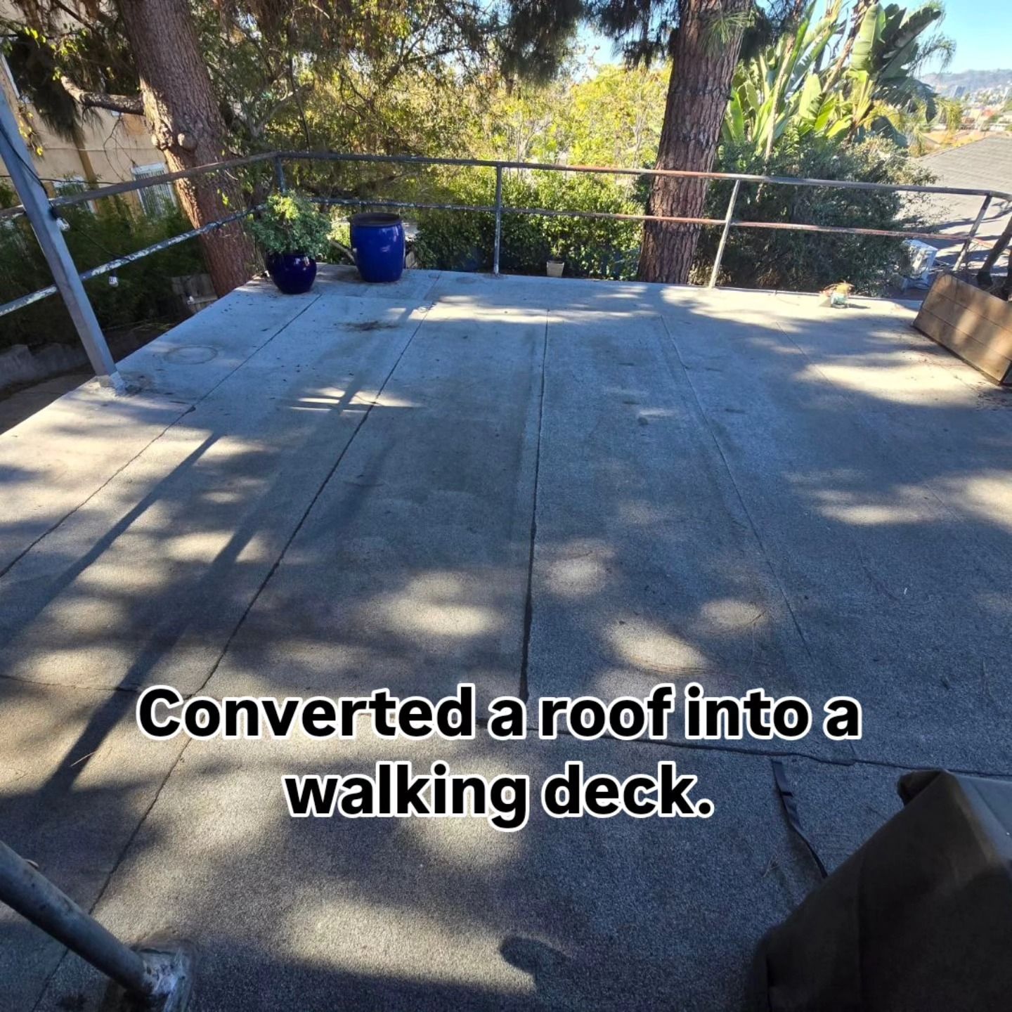 Converted roof into a walking deck with a flat surface, trees, and potted plants.
