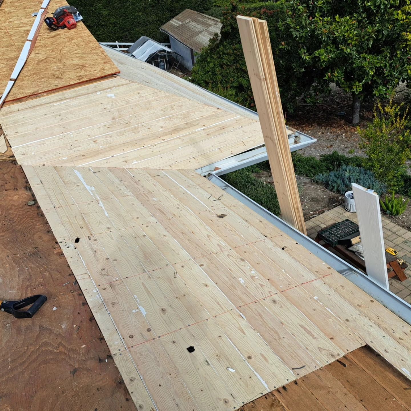 Wooden roof deck under construction with plywood sheathing and a person working in the distance