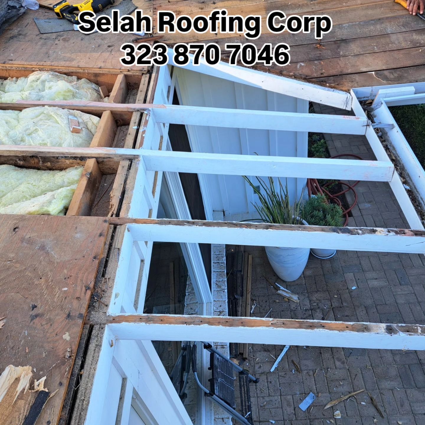 Roof repair with exposed rafters and white-framed window, showing insulation and construction debris.