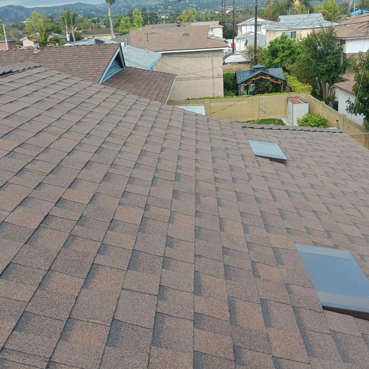 Roof shingles with skylights overlooking suburban homes and distant hills