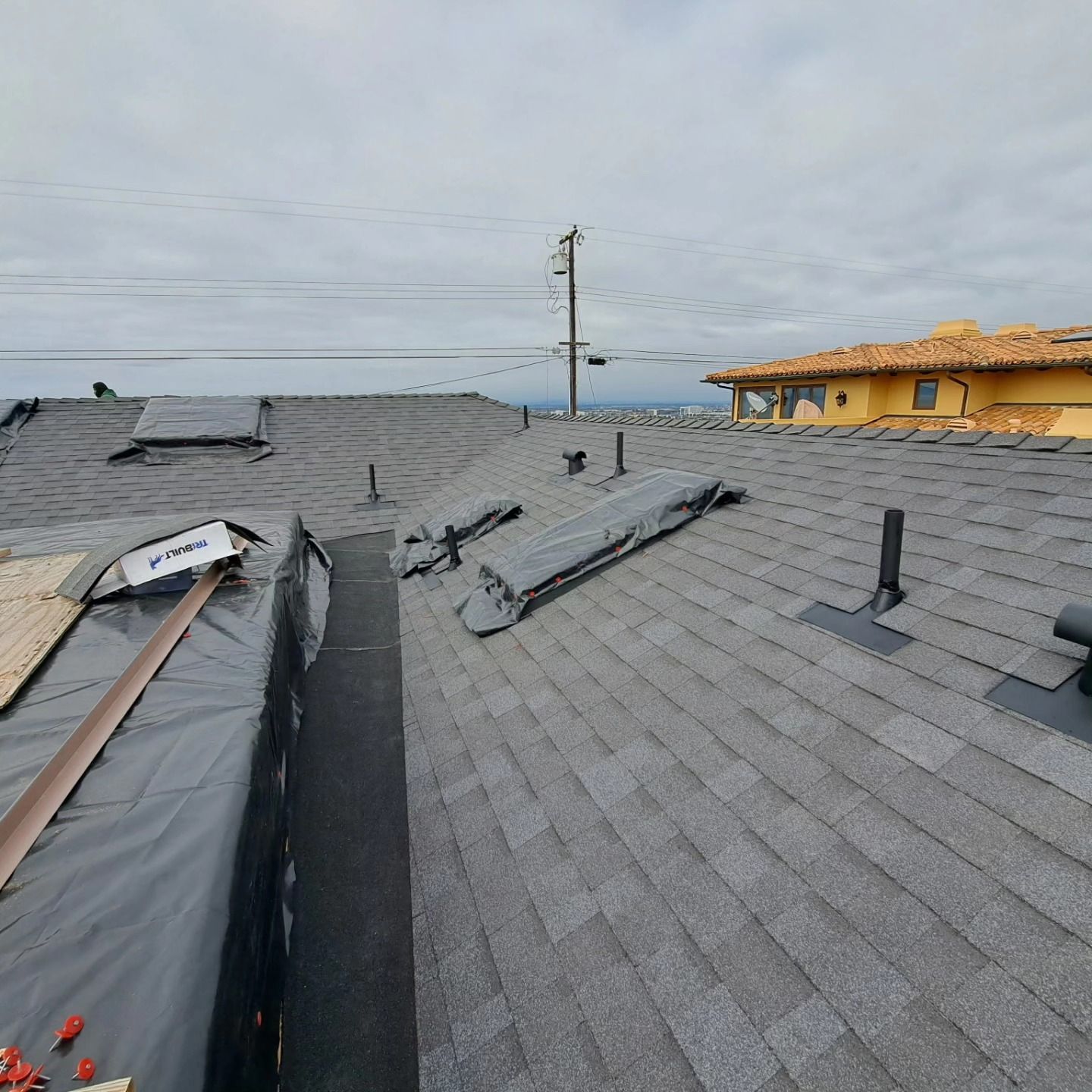 Roof damaged by storm, with missing shingles and exposed underlayment under a cloudy sky.
