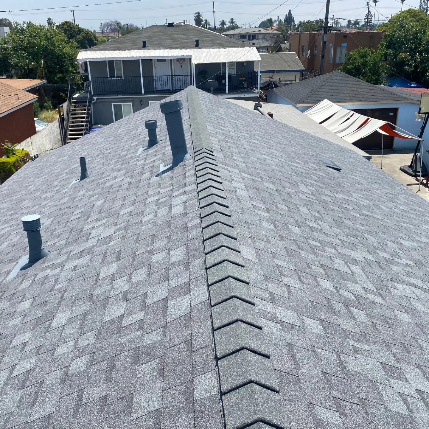 Gray shingle roof with vents, viewed from above in a residential neighborhood