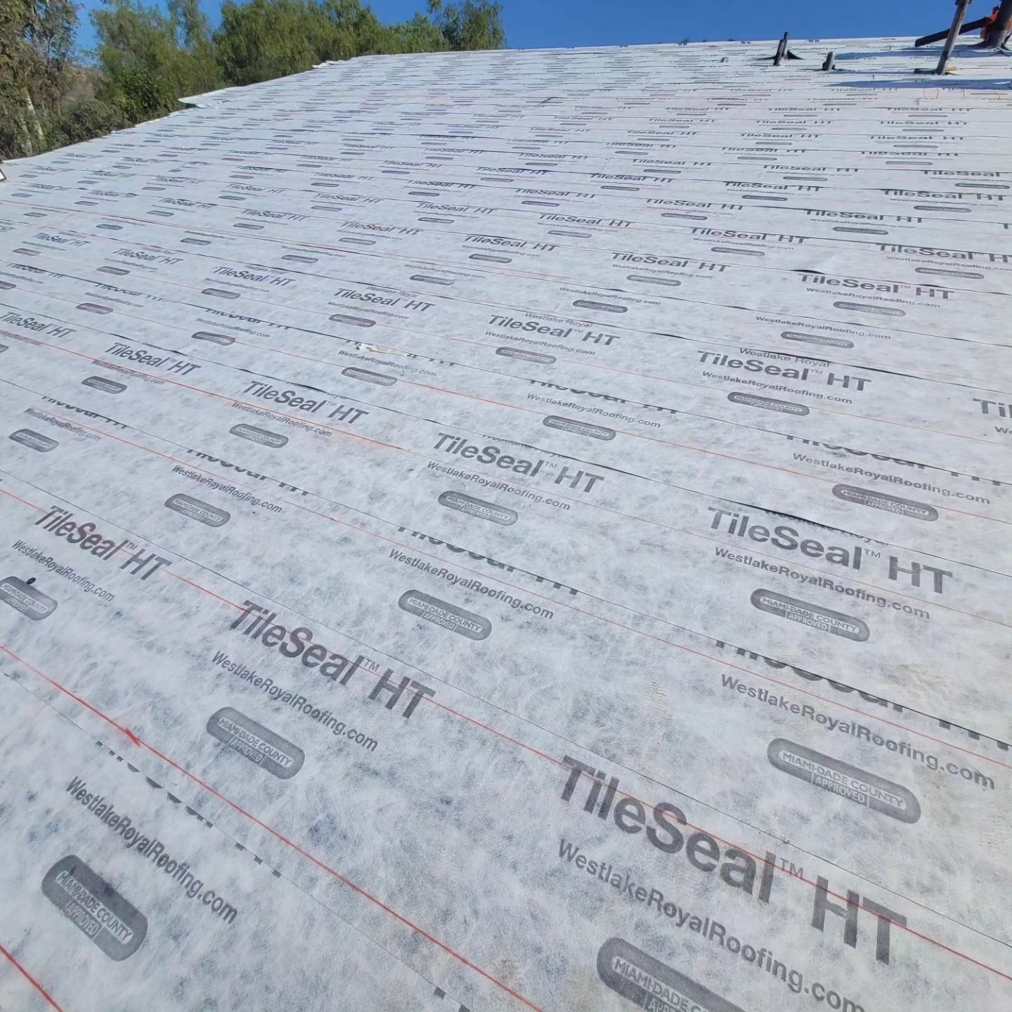 Roof deck covered in white TileSeal HT underlayment with red guide lines, under construction outdoors