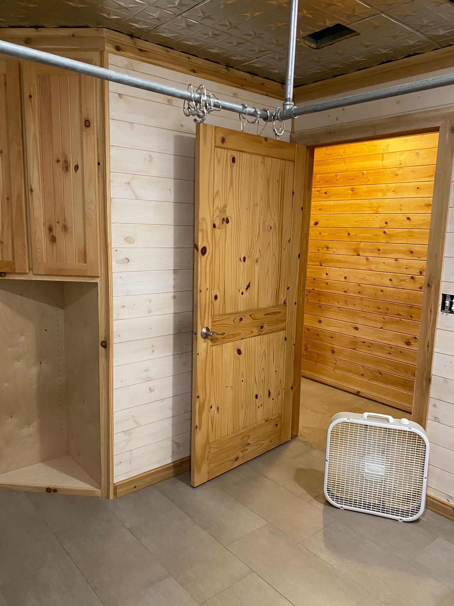 A fan is sitting on the floor next to a wooden door in a room.