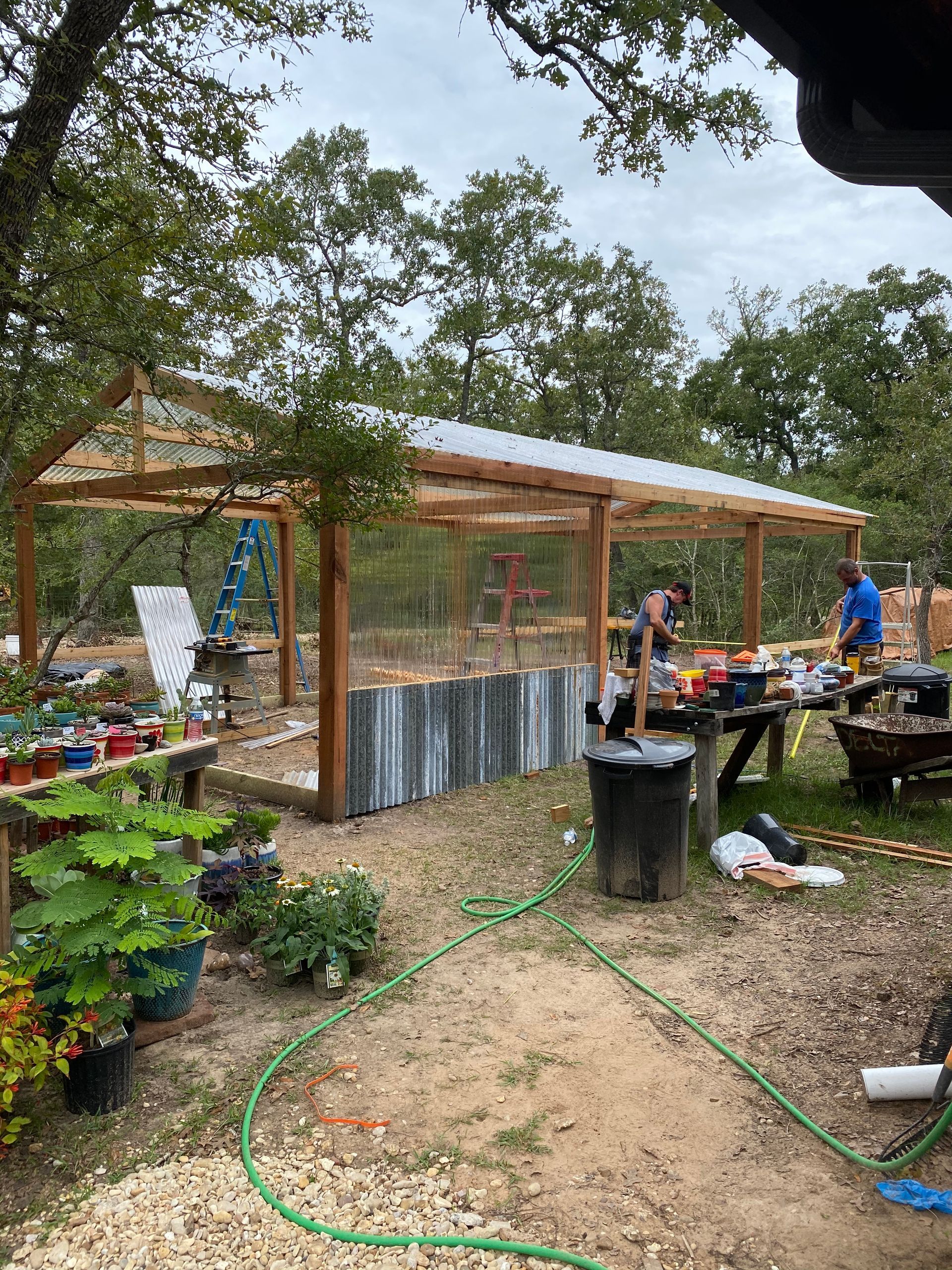 A group of people are working on a greenhouse in a backyard.