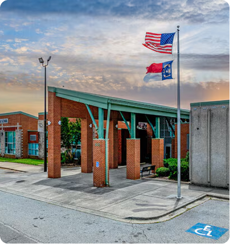 Brick civic building with U.S. and Arkansas flags by the entrance on a cloudy day
