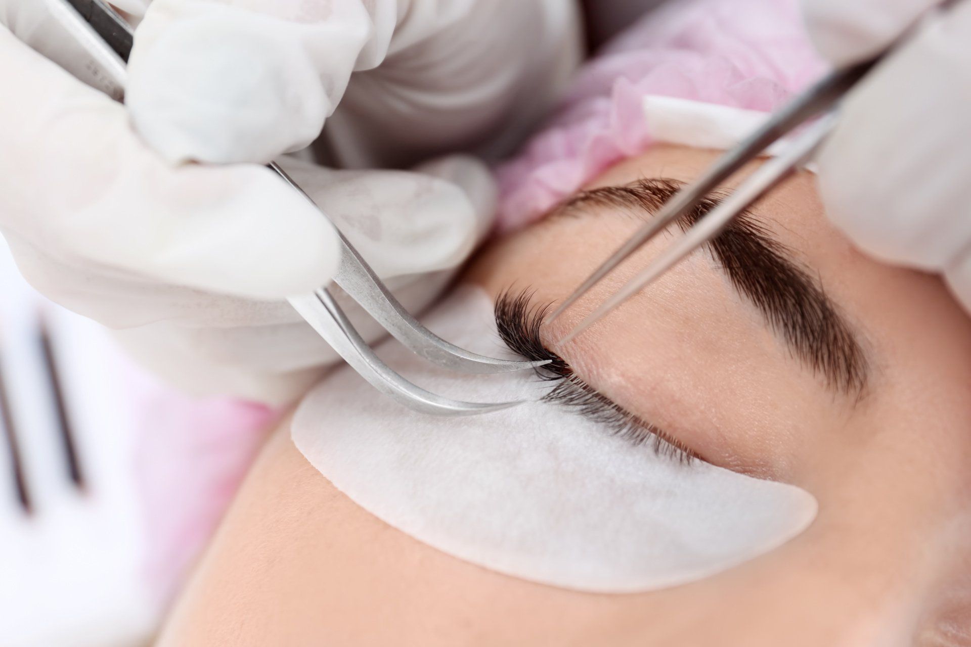 a lash technician applying hybrid lashes on a client