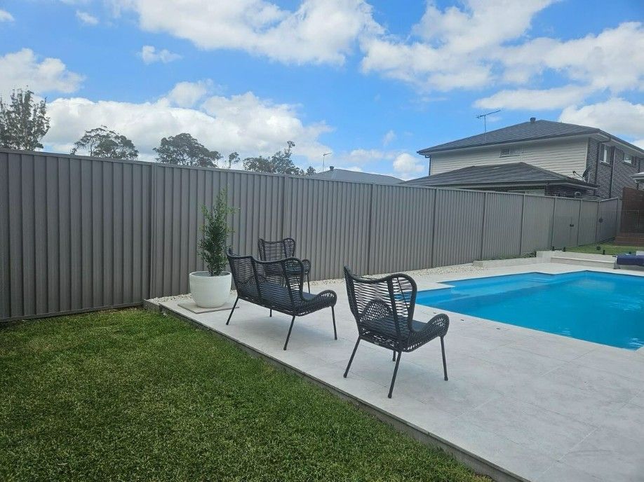 A Fence Surrounds a Swimming Pool in a Backyard — JOA - Construction & Maintenance Pty Ltd in Appin, NSW